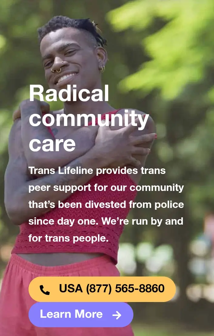 A smiling trans person in a red top and pink shorts hugs themselves outdoors with green foliage in the background. Overlaid…