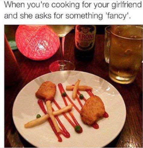 A plate of two fried chicken nuggets and a few french fries arranged with ketchup drizzles and green peas, presented as a…