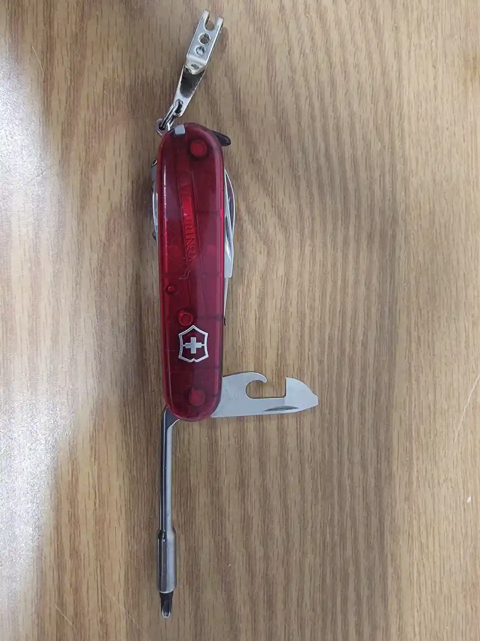 A red Victorinox Swiss Army knife with multiple tools extended lies on a wooden surface. The text overlay reads 'i'm not…