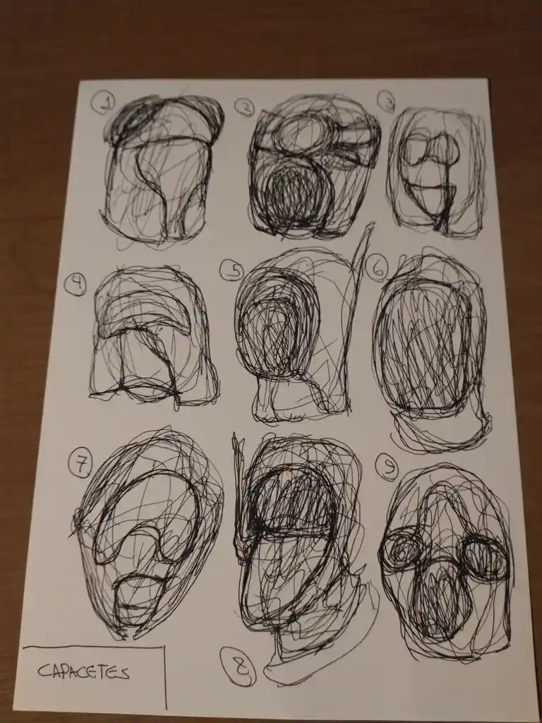A hand-drawn sheet shows nine rough, scribbled sketches of human heads, each labeled 1 through 9, arranged in a 3x3 grid on…