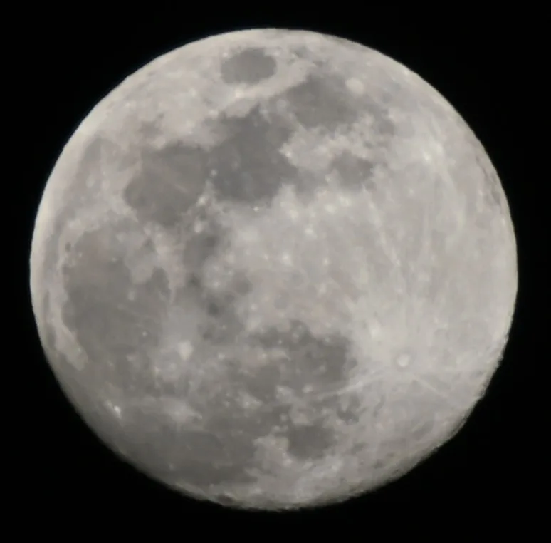 A close-up photograph of the full moon against a black sky, showing its cratered and textured surface. Overlaid text in…