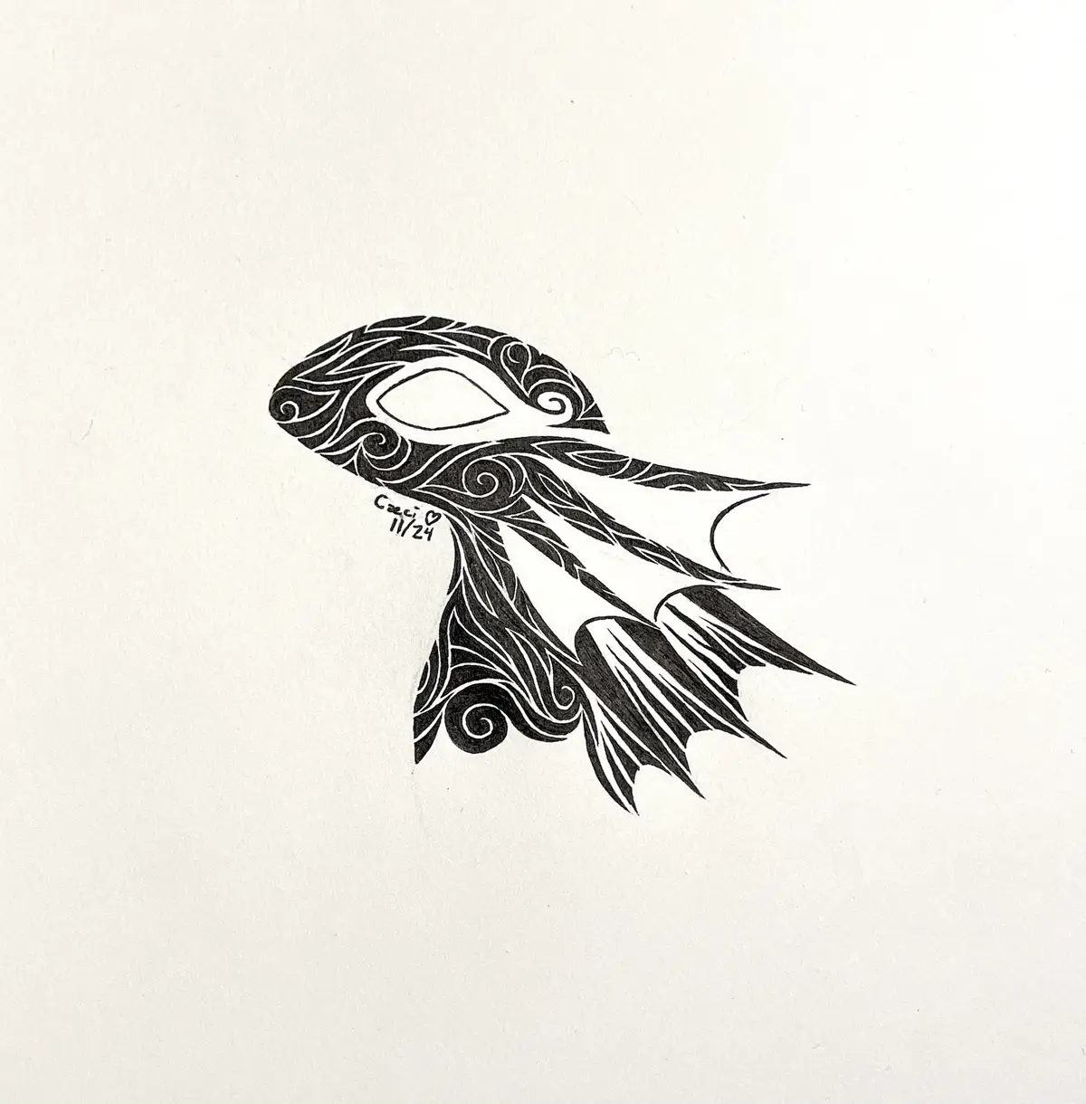 A black and white ink drawing on textured paper depicts a stylized fish with intricate swirling patterns filling its body…