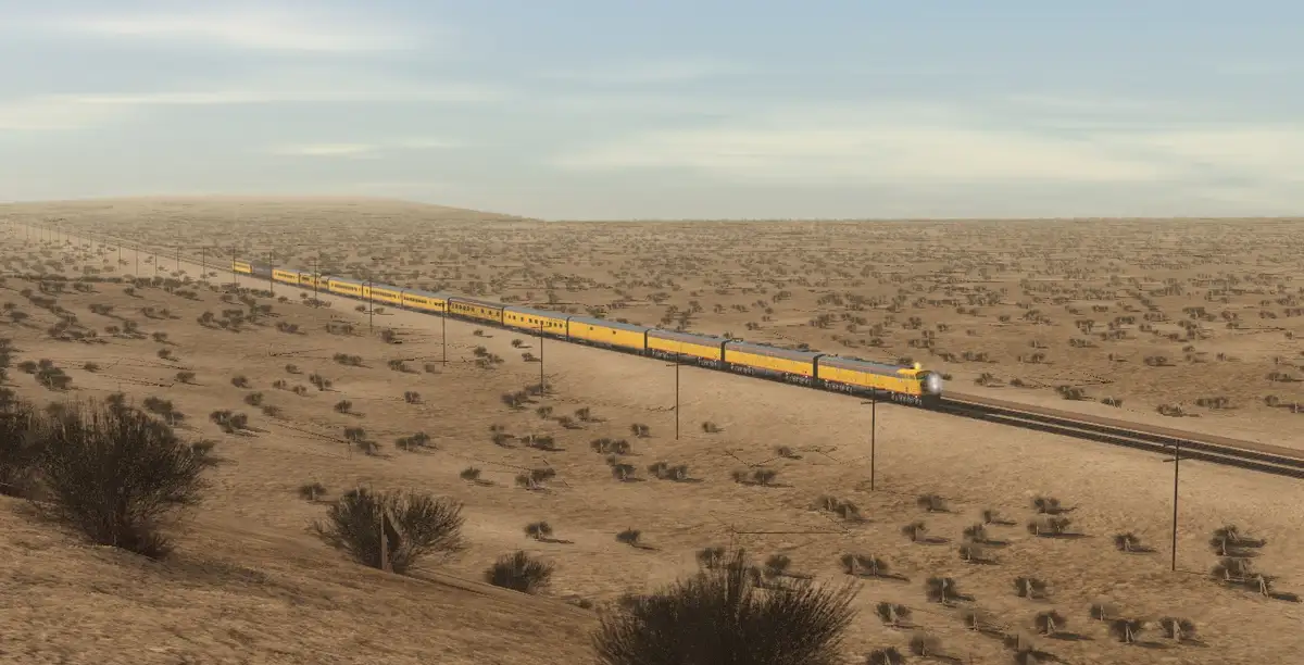 A long yellow train travels across a vast, arid desert landscape under a pale sky. The train stretches far into the horizon…