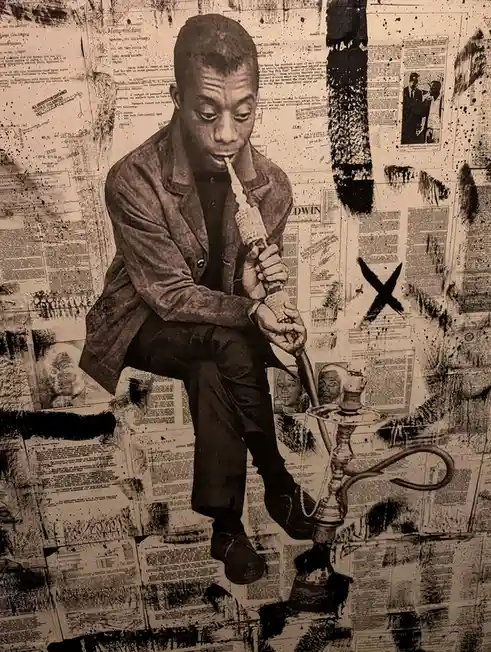 A black-and-white image shows a man in a suit holding a hookah pipe to his mouth, standing before a wall covered in…
