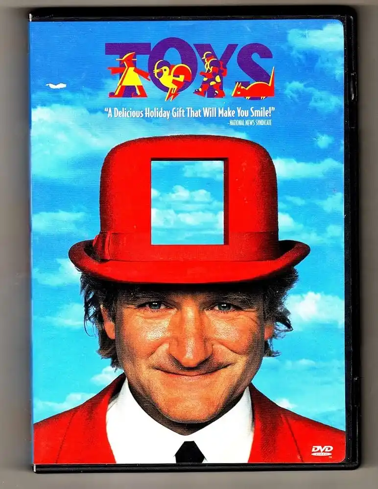 The image shows the DVD cover for the movie 'Toys,' featuring a smiling man in a red suit and a red top hat with a square…