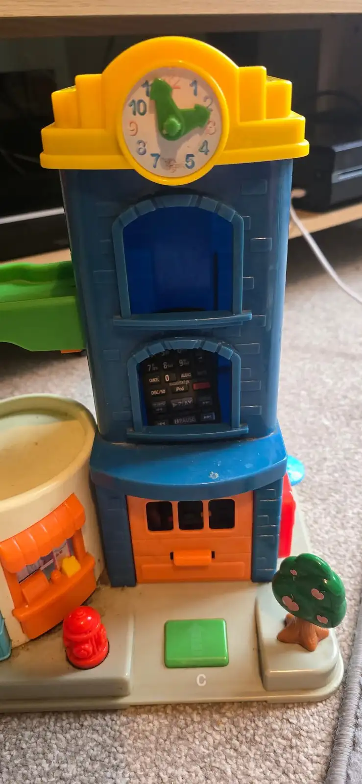 A toy building with a clock tower and a built-in remote control panel, overlaid with the text 'i'm not lazy, i'm just…