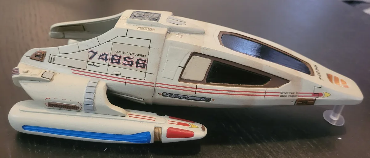 A close-up photo of a white Starfleet shuttlecraft model, identified as 'U.S.S. VOYAGER 74656' and 'SHUTTLE 4 COCHRANE'…