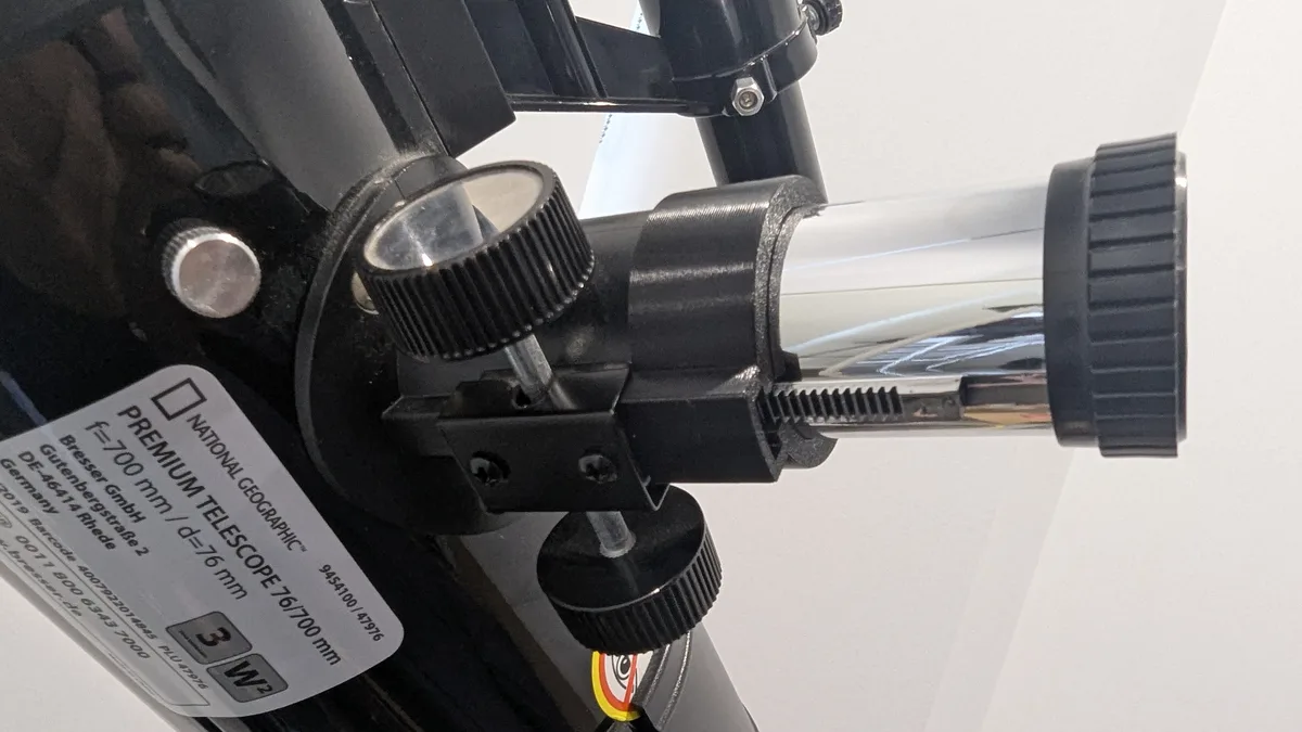 A close-up of a black National Geographic branded telescope with a label showing 'PREMIUM TELESCOPE 76/700 mm' and technical…