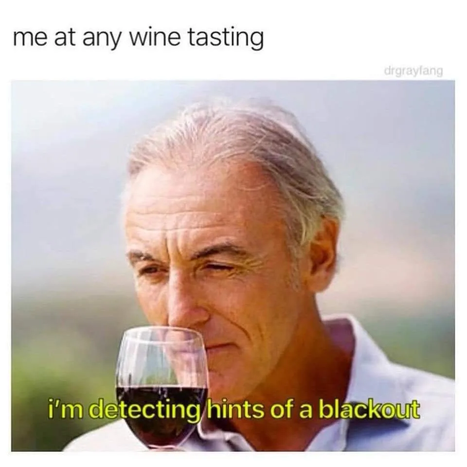 A man with gray hair, wearing a light-colored collared shirt, is shown holding a wine glass to his nose and sniffing the…