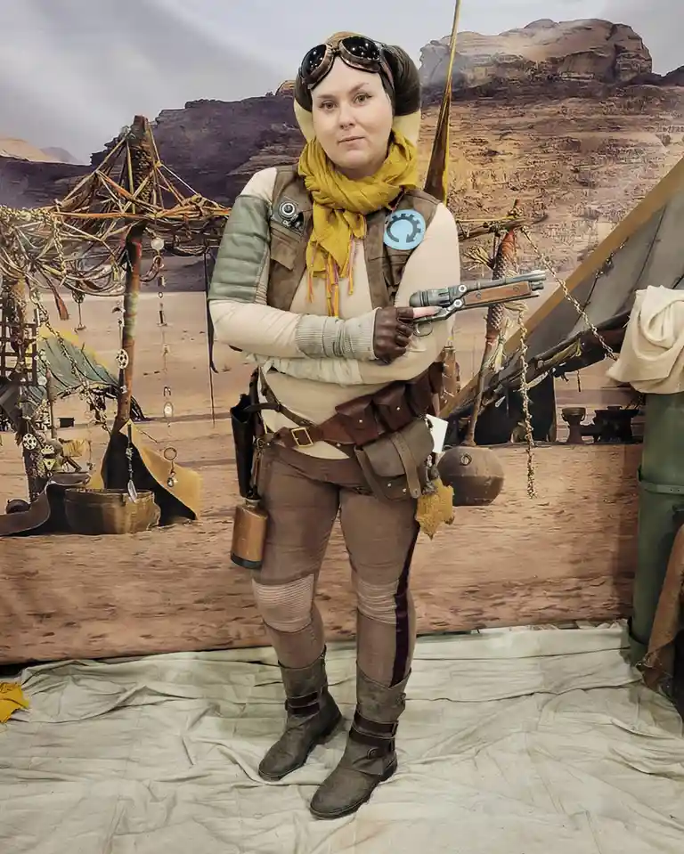 A person in a detailed Star Wars cosplay, resembling a character from the 'Star Wars: Andor' series, stands confidently in…