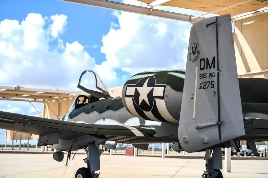 A vintage military fighter plane, likely a P-51 Mustang, is parked under a hangar with its cockpit canopy open. The…