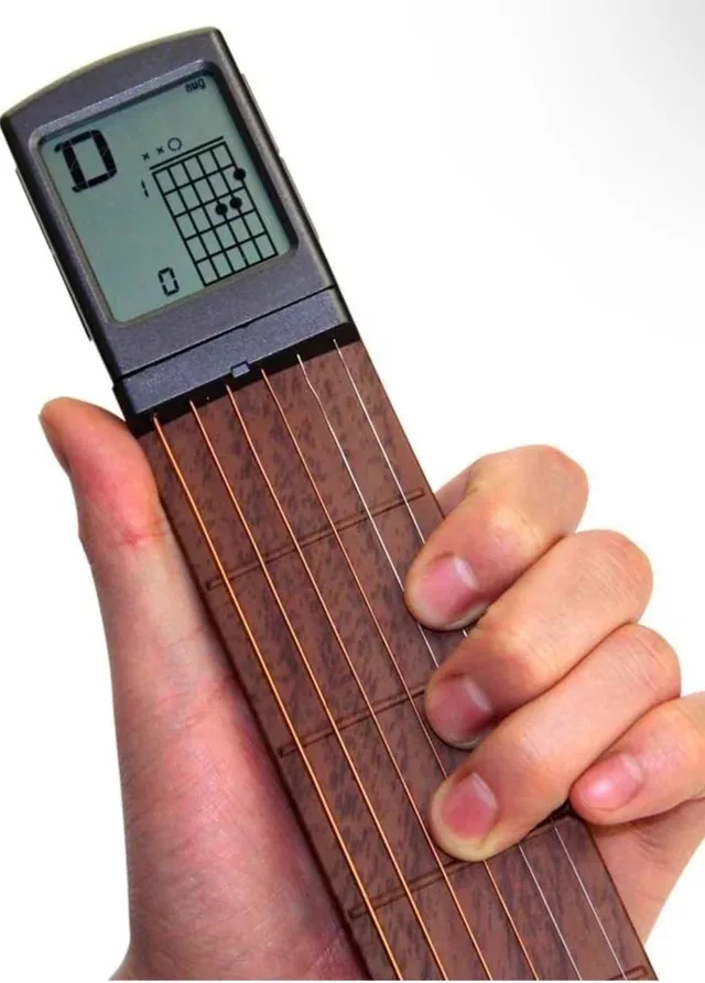 A hand holds a small, portable guitar learning device with a digital screen displaying a 'D' chord diagram. The screen shows…