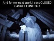 A person in a white robe and wide-brimmed hat, resembling a wizard, holds a shotgun in a dimly lit, possibly attic or…