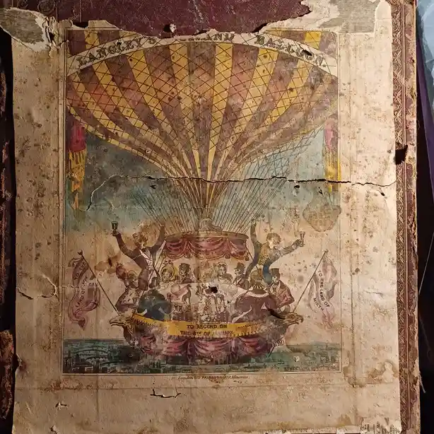 An aged, torn poster depicts a large, ornate hot air balloon with a festive gondola full of people celebrating, holding…