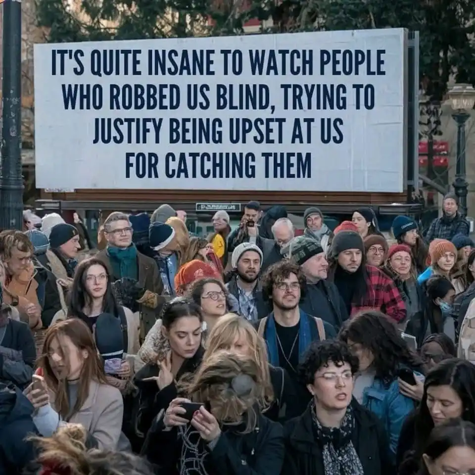 A crowd of people in winter clothing looks upward toward a large white sign with bold black text. The sign reads: 'IT'S…