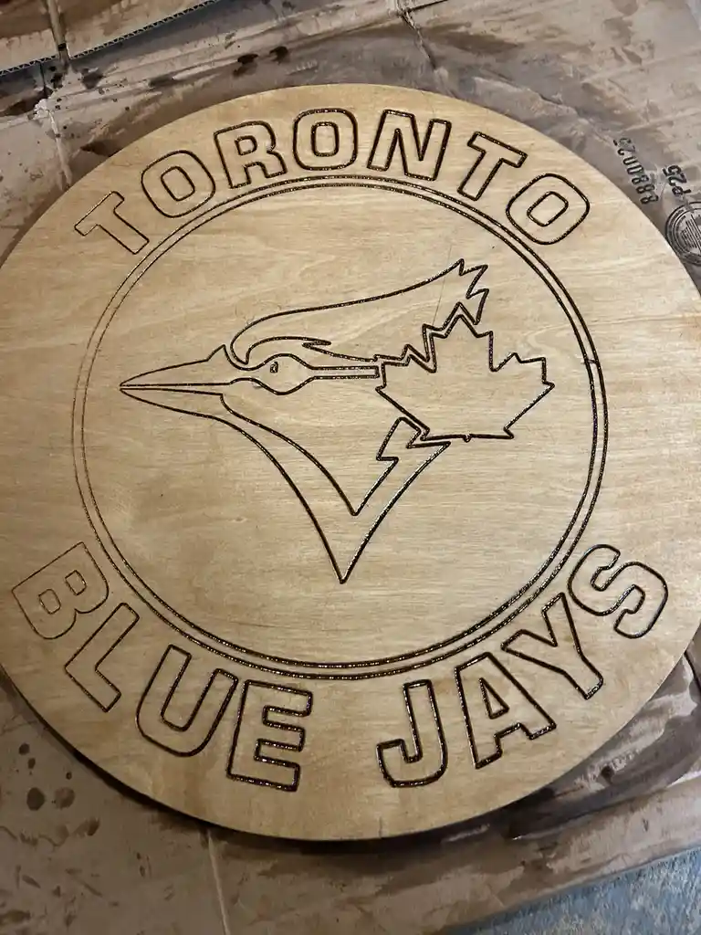 A circular wooden sign features the Toronto Blue Jays logo, with the words 'TORONTO' arched above and 'BLUE JAYS' below…