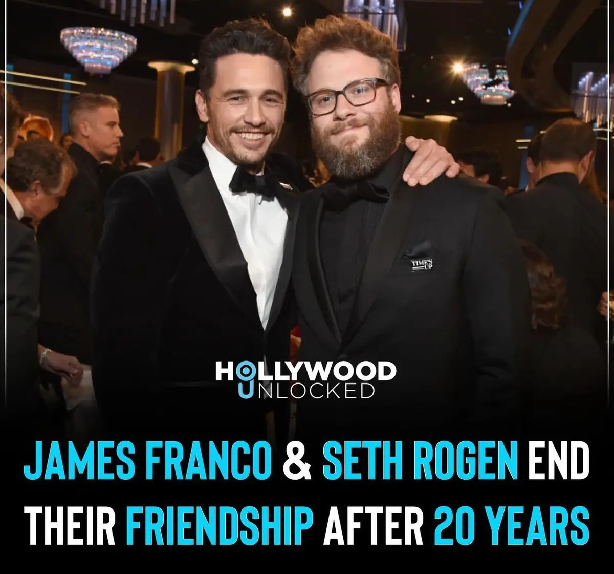 Two men in tuxedos, James Franco and Seth Rogen, pose together at a formal event with chandeliers and other guests in the…