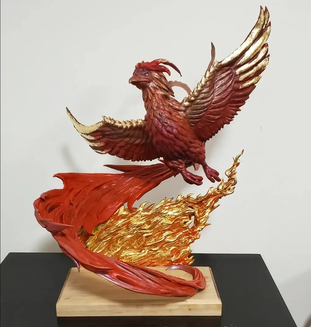 A detailed sculpture of a phoenix, painted in red and gold, is shown mid-flight atop a wooden base with stylized flames. The…