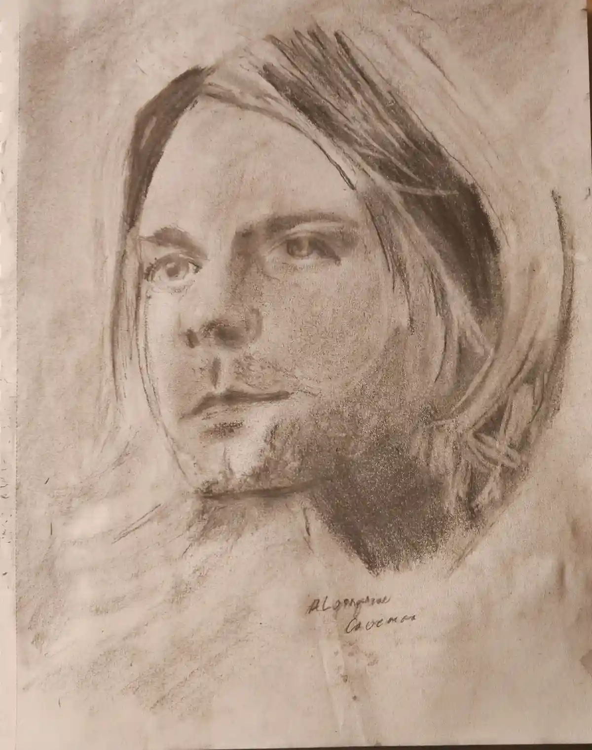 A sepia-toned charcoal sketch of a man with long hair and a beard, looking directly at the viewer. The drawing is signed in…