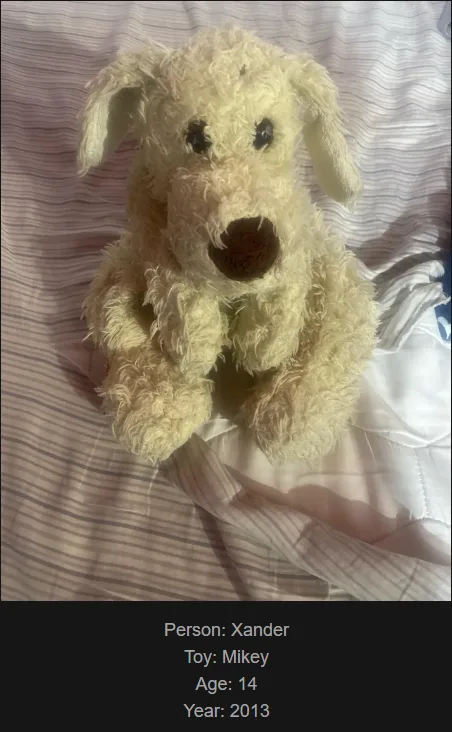 A fluffy, off-white stuffed dog toy with dark button eyes and a brown nose sits upright on striped bedding. Overlaid text…