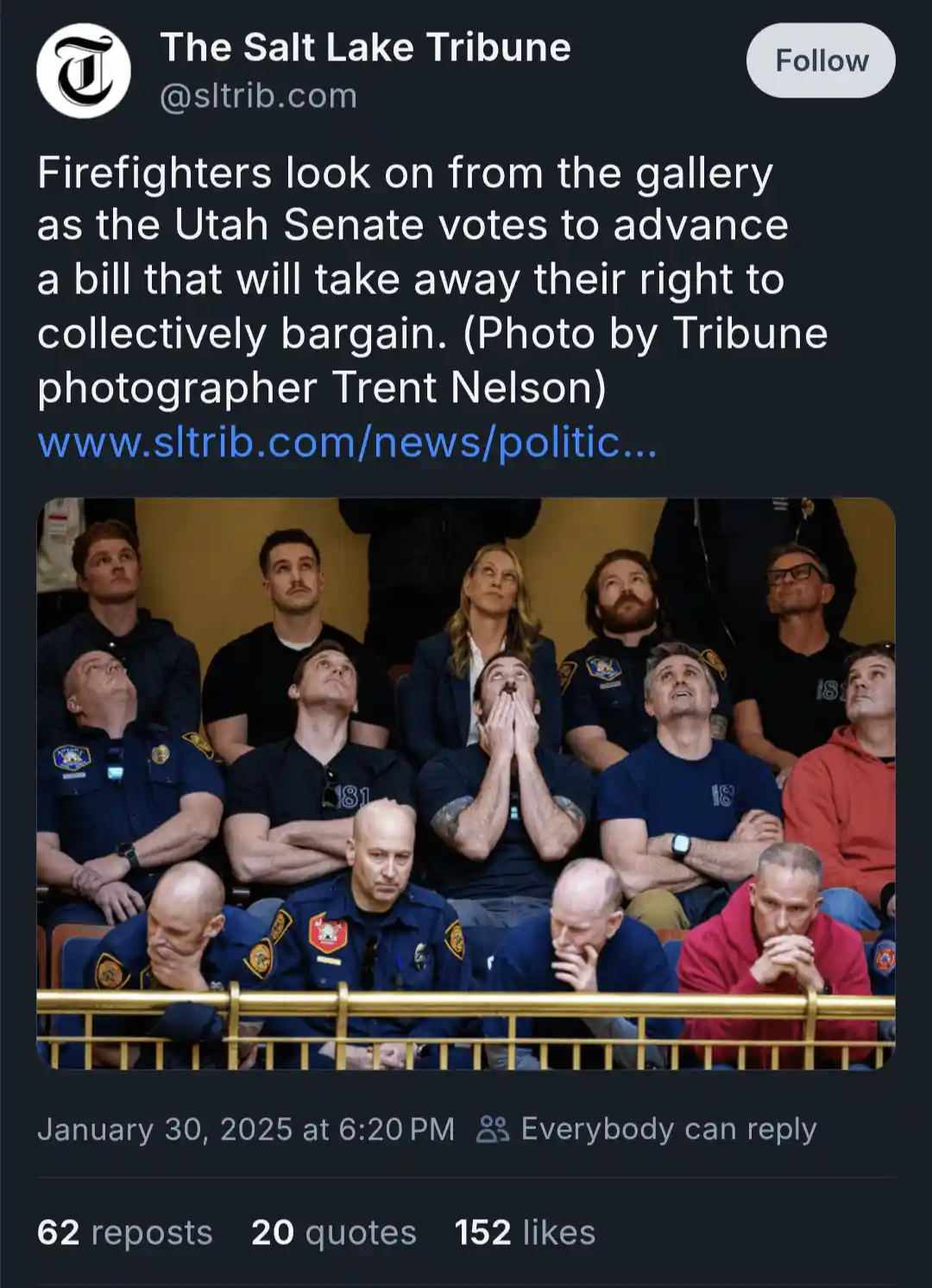A group of firefighters, some in uniform and others in casual clothes, are seated in a gallery looking upward with…