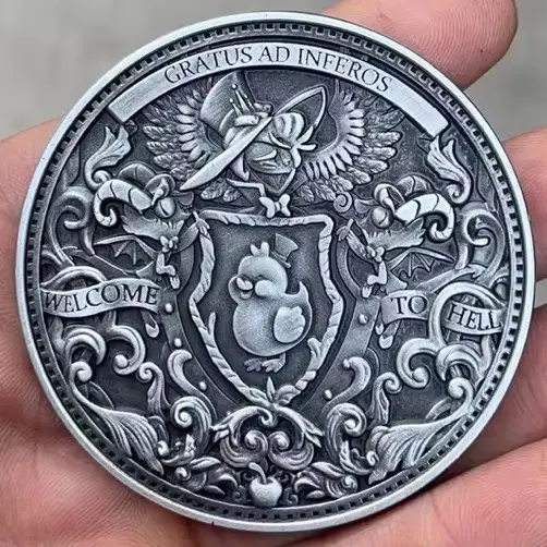A hand holds a detailed, silver-colored medallion featuring ornate scrollwork, a central shield with a small bird wearing a…