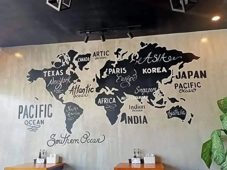 A wall mural of a world map where continents are labeled with names of countries or cities that are not geographically…
