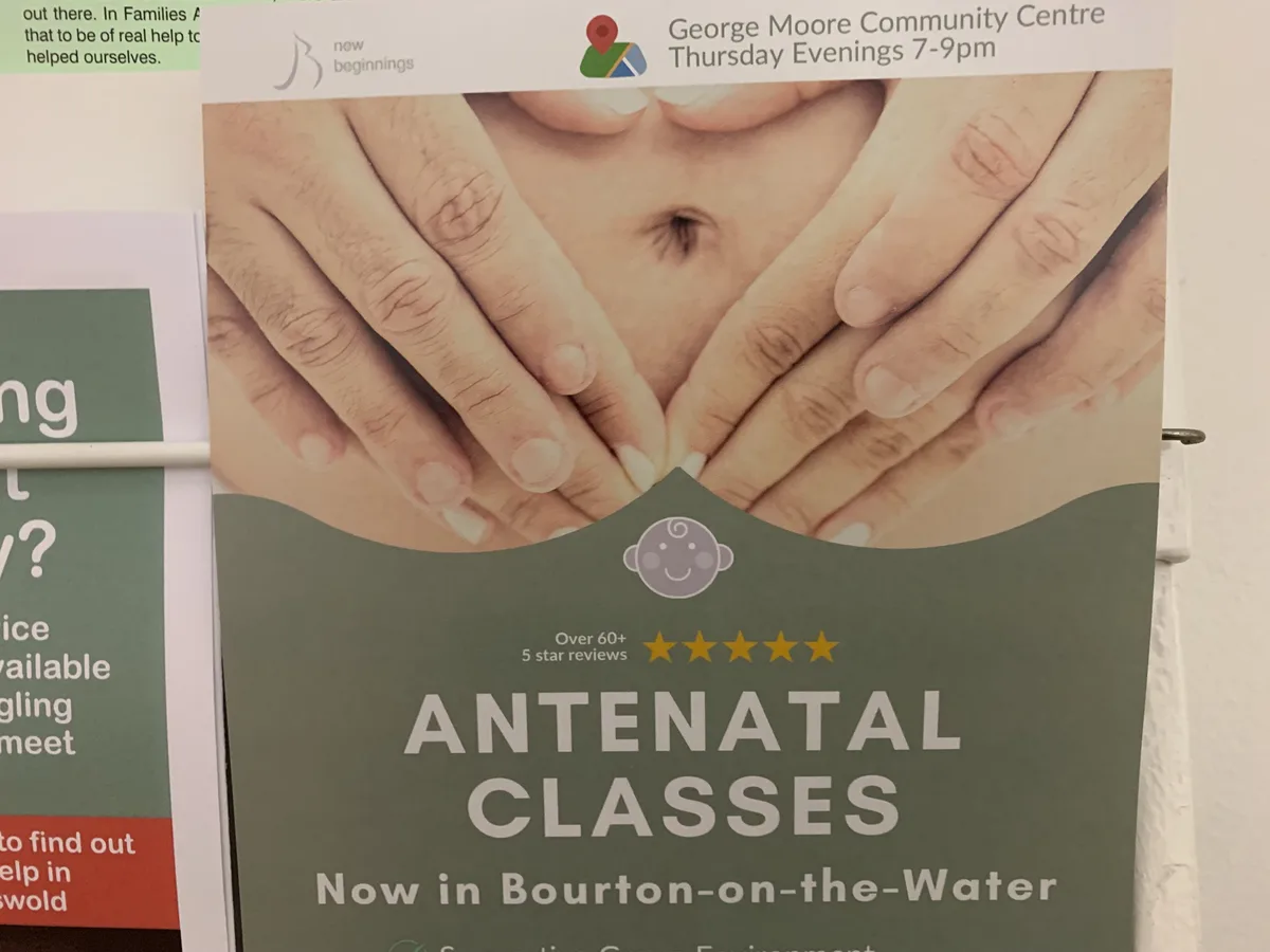 A poster advertising antenatal classes features a photo of two hands gently cradling a pregnant belly, with text indicating…