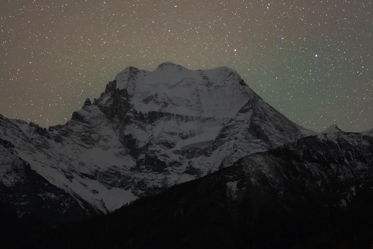 The image shows a sequence of three panels depicting a snowy mountain peak under a starry night sky. In the first panel, a…