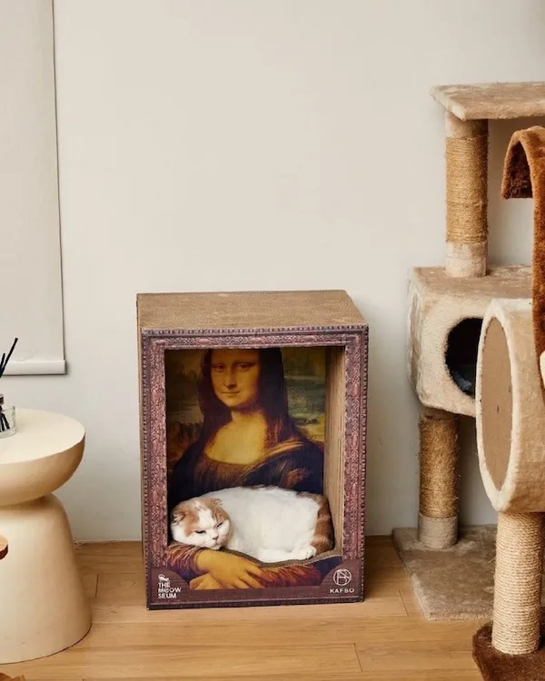 a white and ginger cat is sleeping peacefully in the lap of a replica of Leonardo da Vinci's Mona Lisa painting, which is…