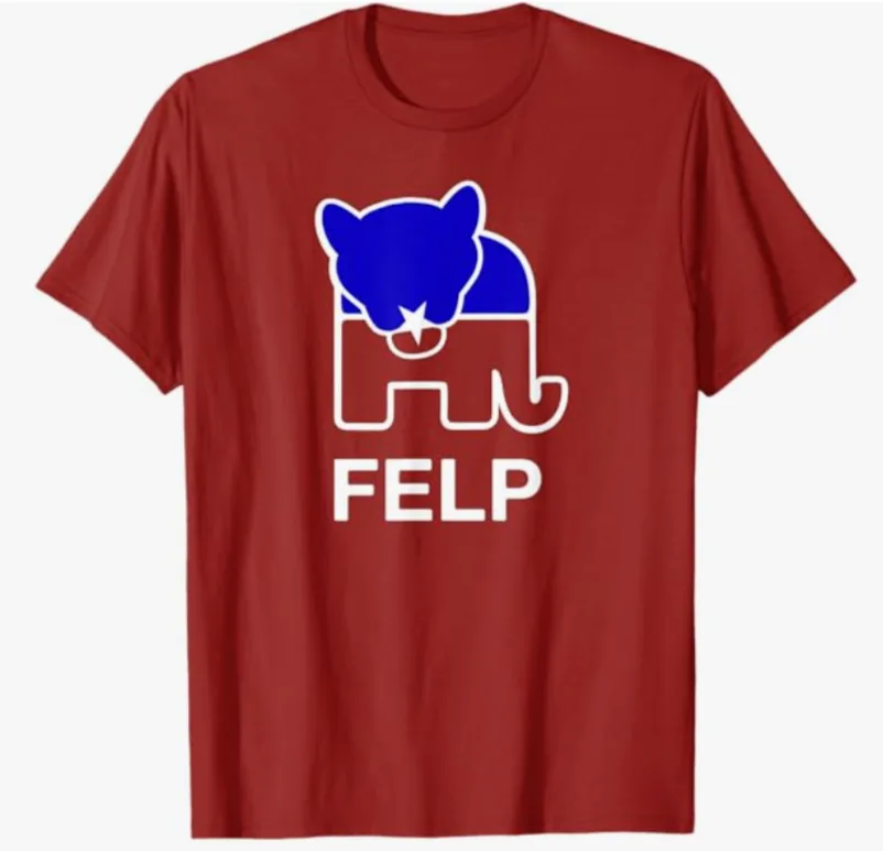 A red t-shirt displays a white outline of an elephant with a blue bear head superimposed on its upper body, and the word…