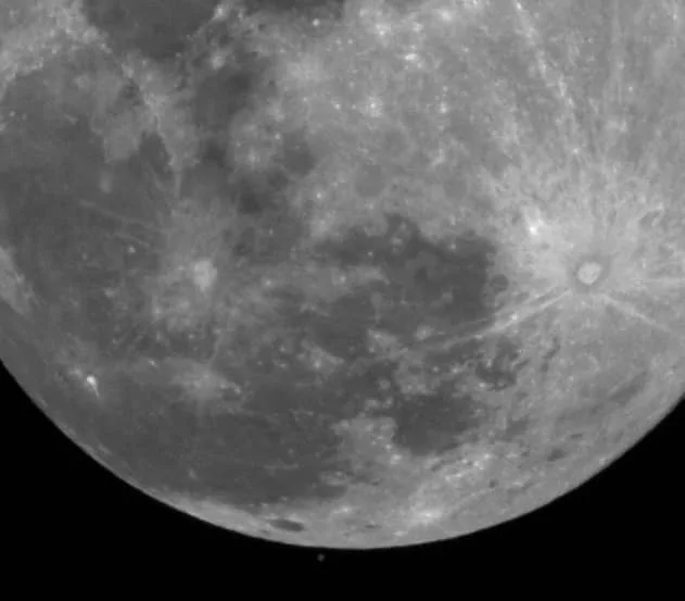 A grayscale, high-resolution image of the moon's surface, showing craters, maria, and rays emanating from impact sites…
