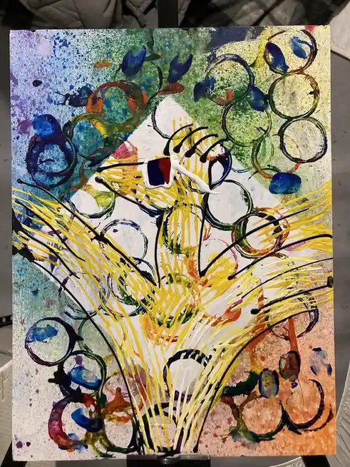 An abstract painting with vibrant splashes of blue, green, yellow, and orange, featuring swirling circles and streaks. A…