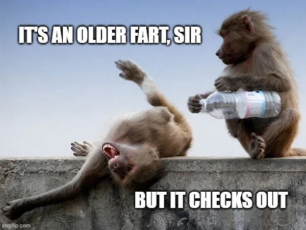 Two baboons sit on a concrete ledge against a clear sky. One baboon lies on its back with mouth wide open, appearing to…