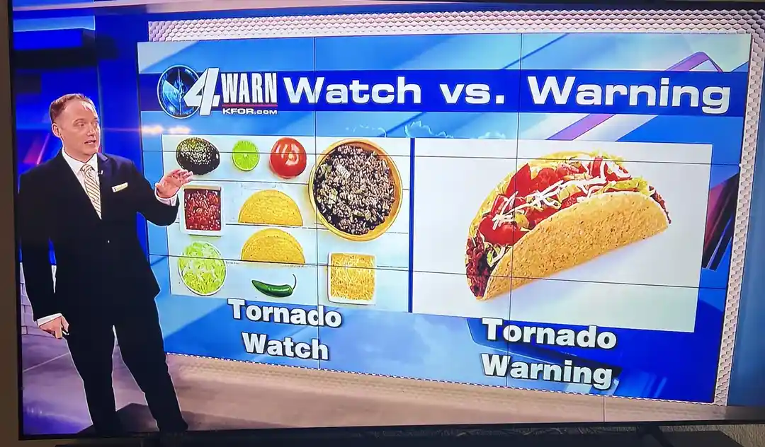 A weather anchor stands beside a screen showing a 'Watch vs. Warning' graphic. The 'Tornado Watch' side displays individual…