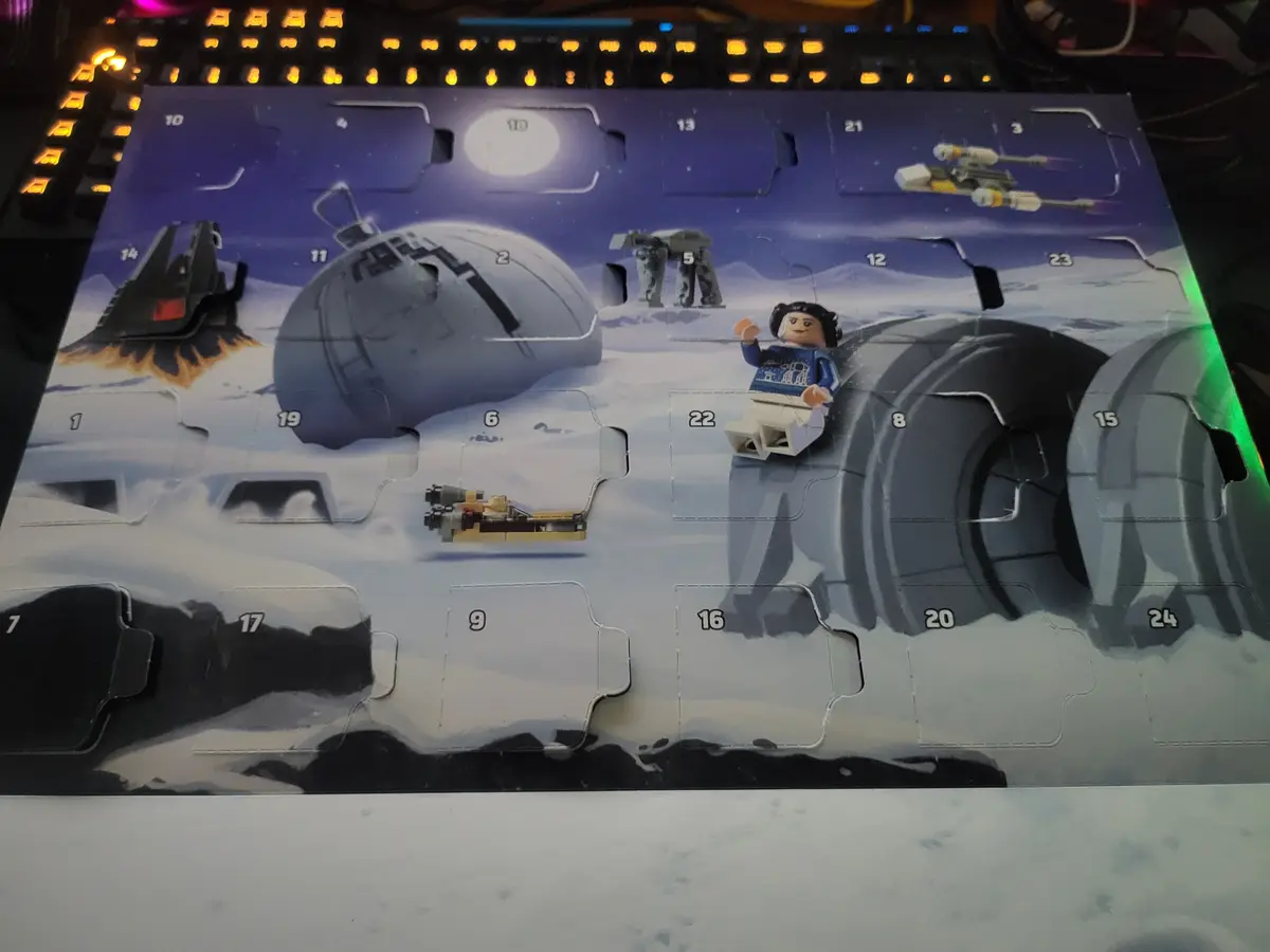 A Lego Star Wars Advent calendar with a snowy Hoth scene, featuring numbered flaps, some opened to reveal mini models like…