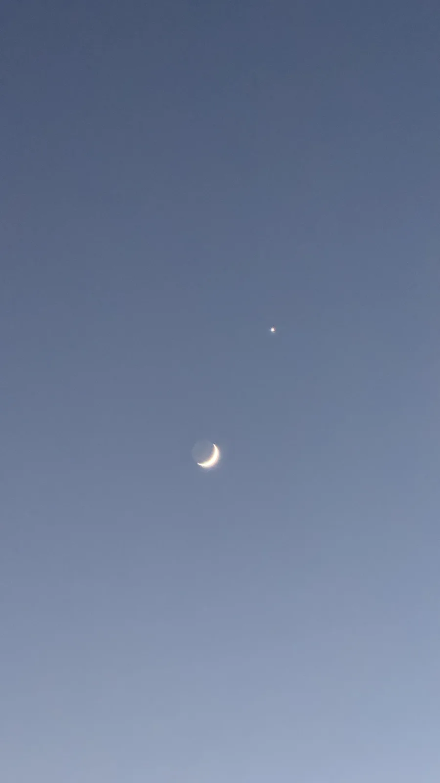 A clear blue sky shows a crescent moon and a bright star positioned above it. Overlaid text reads 'the moon is a spaceship'.