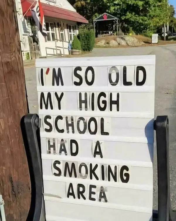 A white, lightbox-style sign with black letter tiles displays the text 'I'M SO OLD MY HIGH SCHOOL HAD A SMOKING AREA'. The…