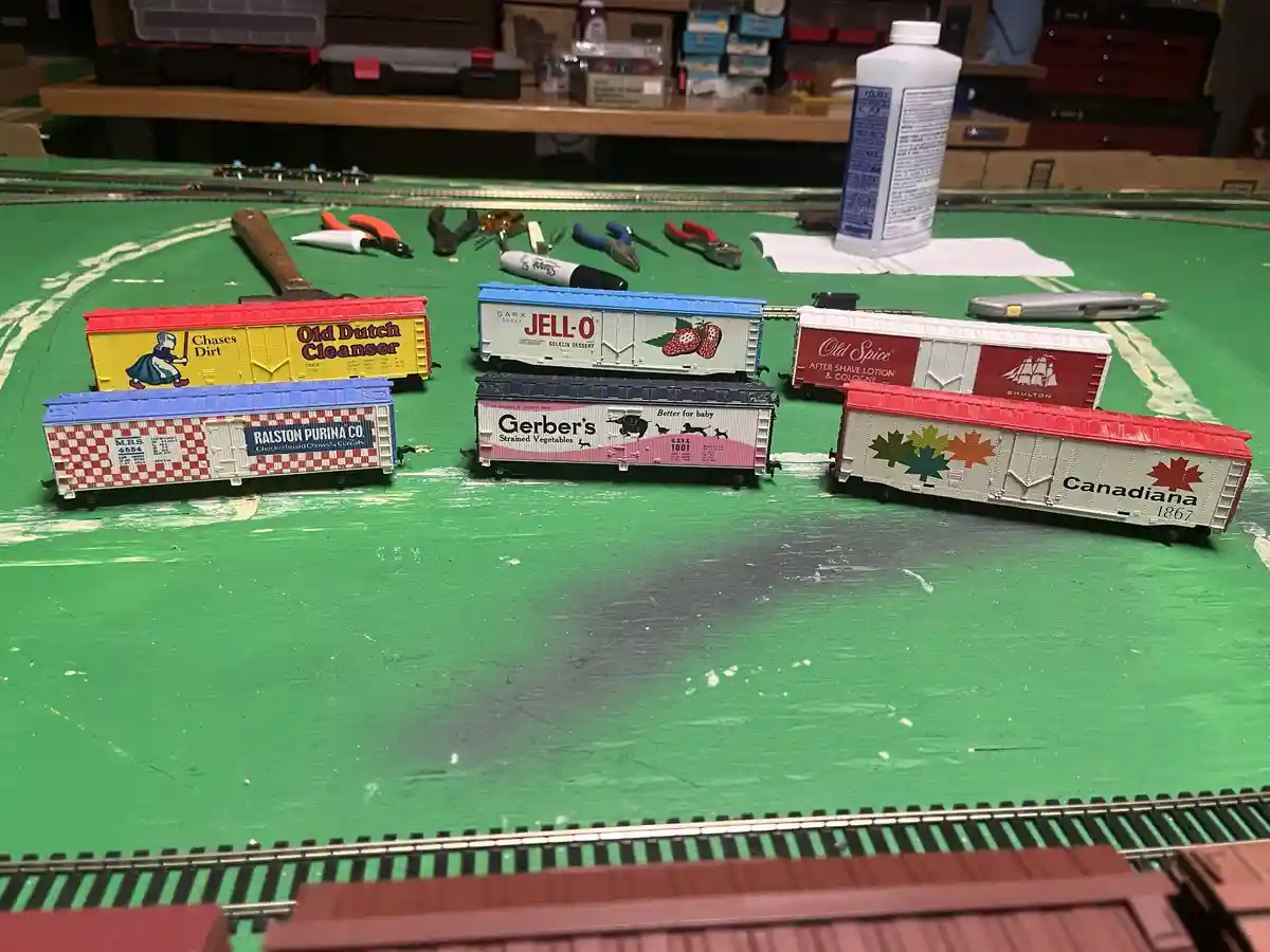 A collection of model train freight cars with vintage brand logos like Old Dutch Cleanser, Jell-O, Old Spice, Ralston…