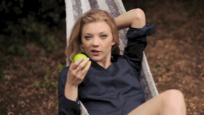 A woman in a dark blue shirt lounges in a hammock outdoors, holding a green apple. In the top row, she brings the apple to…