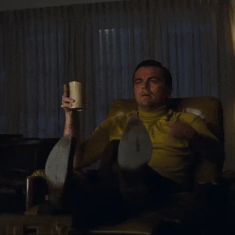 a six-panel grid shows actor Leonardo DiCaprio in a yellow shirt sitting in a chair, holding a mug in one hand and pointing…