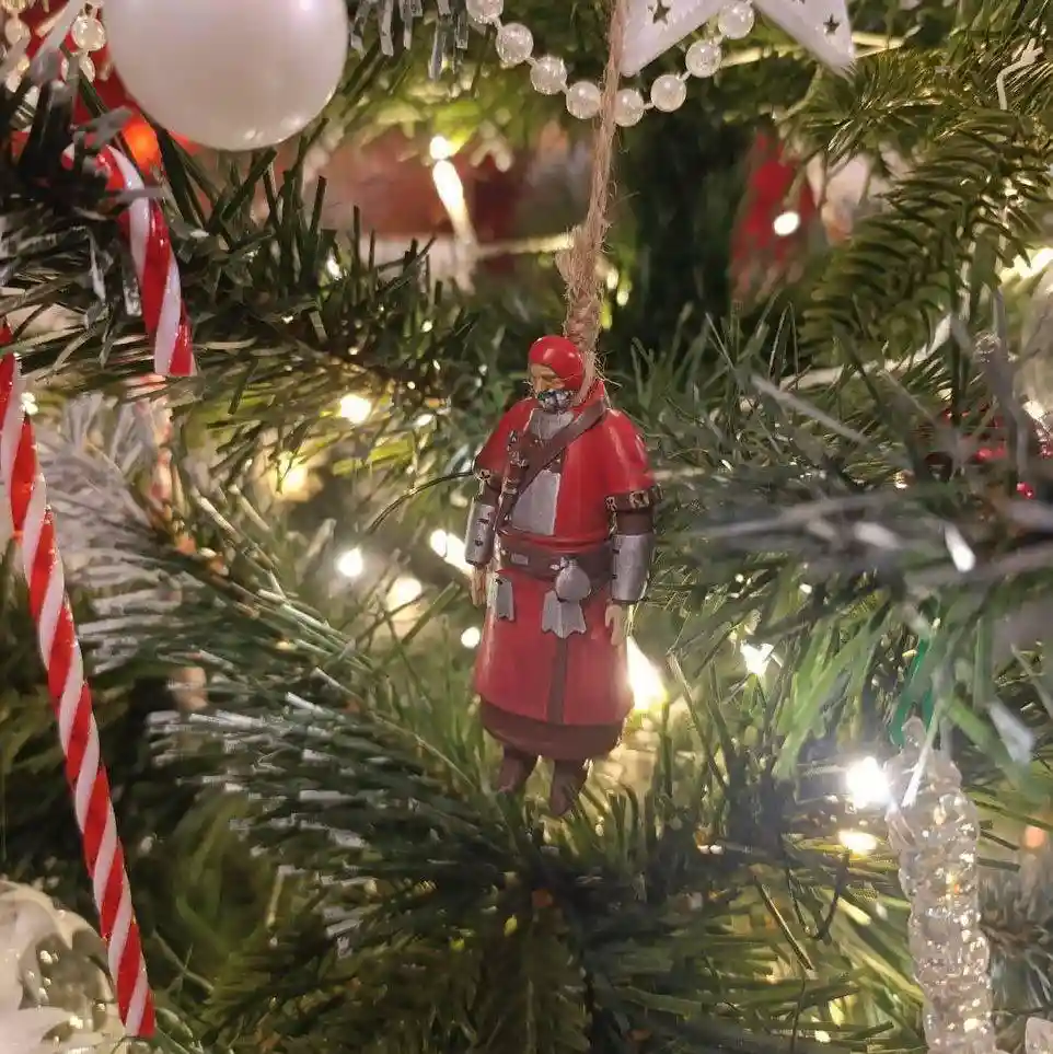 A close-up of a Christmas tree decorated with lights, candy canes, and ornaments. A small figurine of a character resembling…