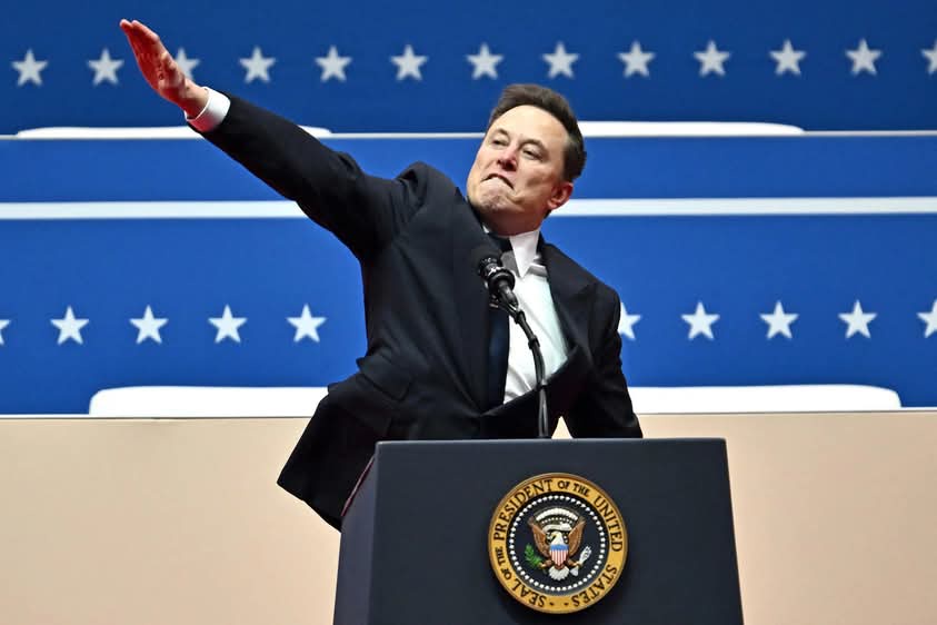 a man in a dark suit stands at a podium bearing the seal of the president of the united states, gesturing with his right arm…