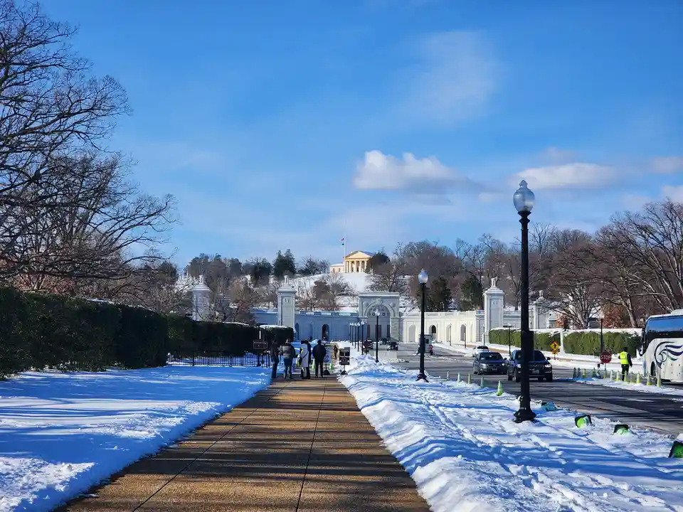 A snowy, sunny day at the National Mall in Washington D.C., with the Jefferson Memorial visible in the distance. People walk…