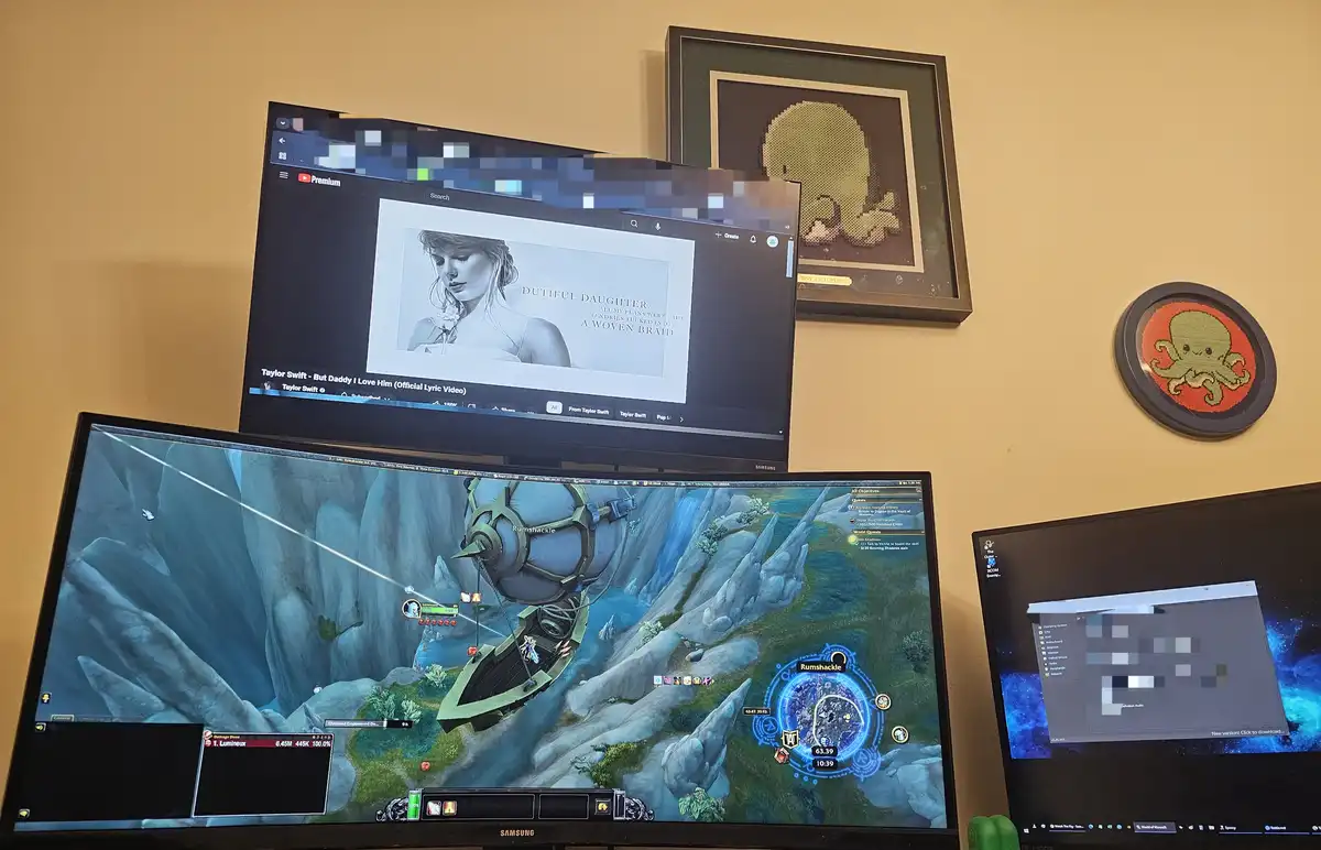 Three computer monitors are shown; the top one displays a YouTube video of Taylor Swift's 'But Daddy I Love Him' lyric video…