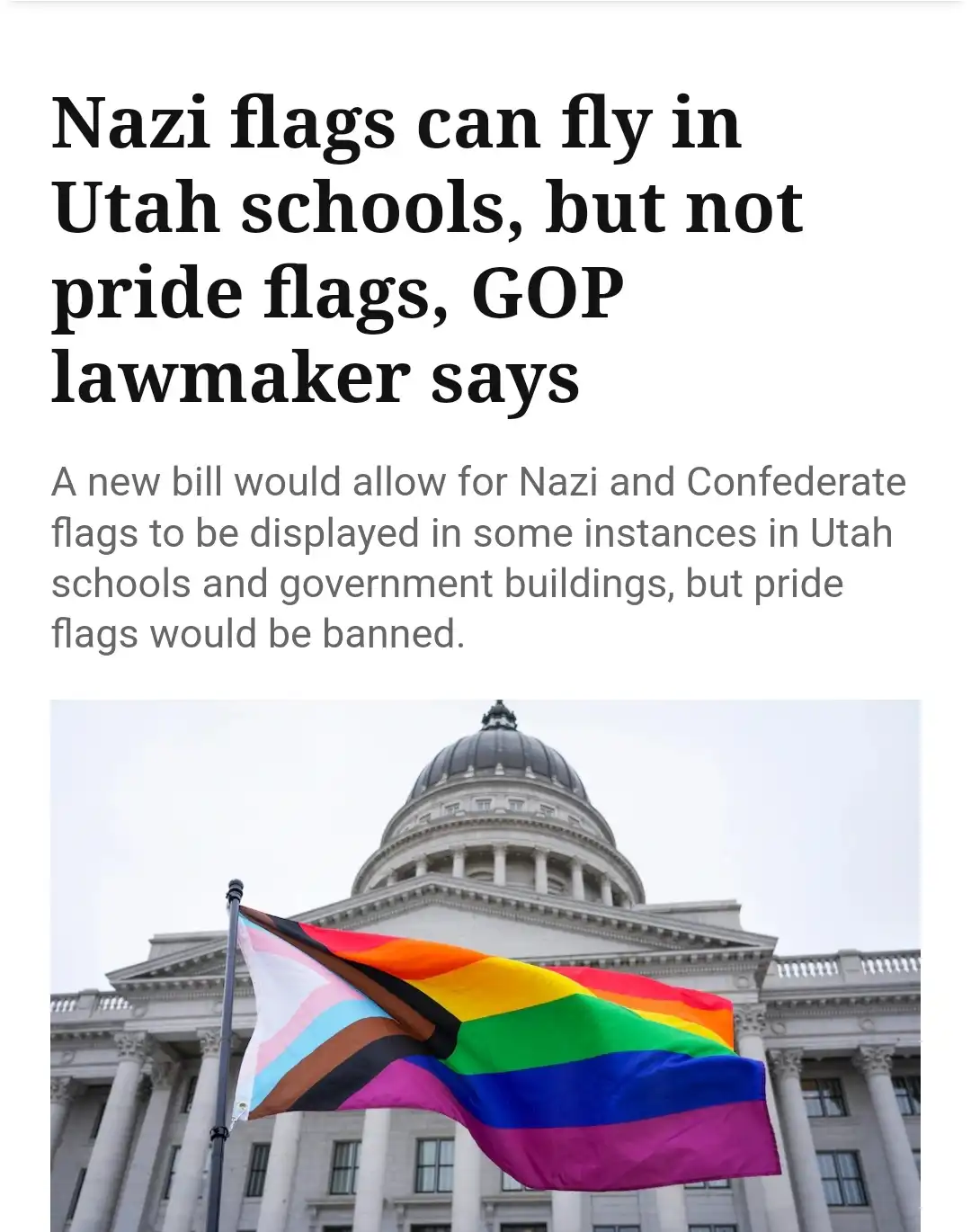 The image shows a rainbow pride flag flying in front of a large, classical-style government building with columns and a…