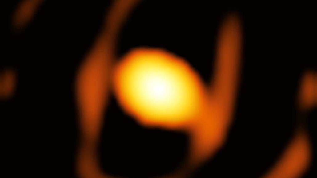 A blurry, out-of-focus image shows a glowing orange-yellow shape against a black background, resembling a hand holding…