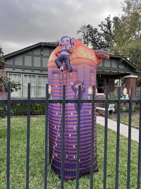 An inflatable Halloween decoration depicting a cartoon man falling from a skyscraper explosion, with another cartoon man in…