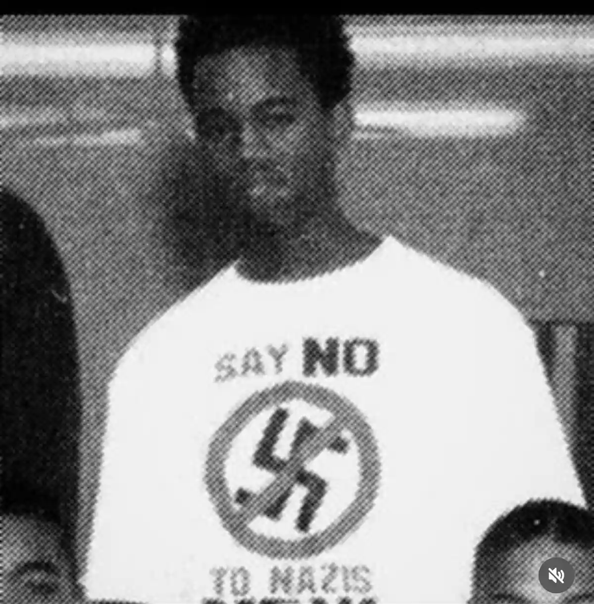 A grainy black-and-white photo shows a person wearing a white t-shirt with the text 'SAY NO TO NAZIS' printed above and…