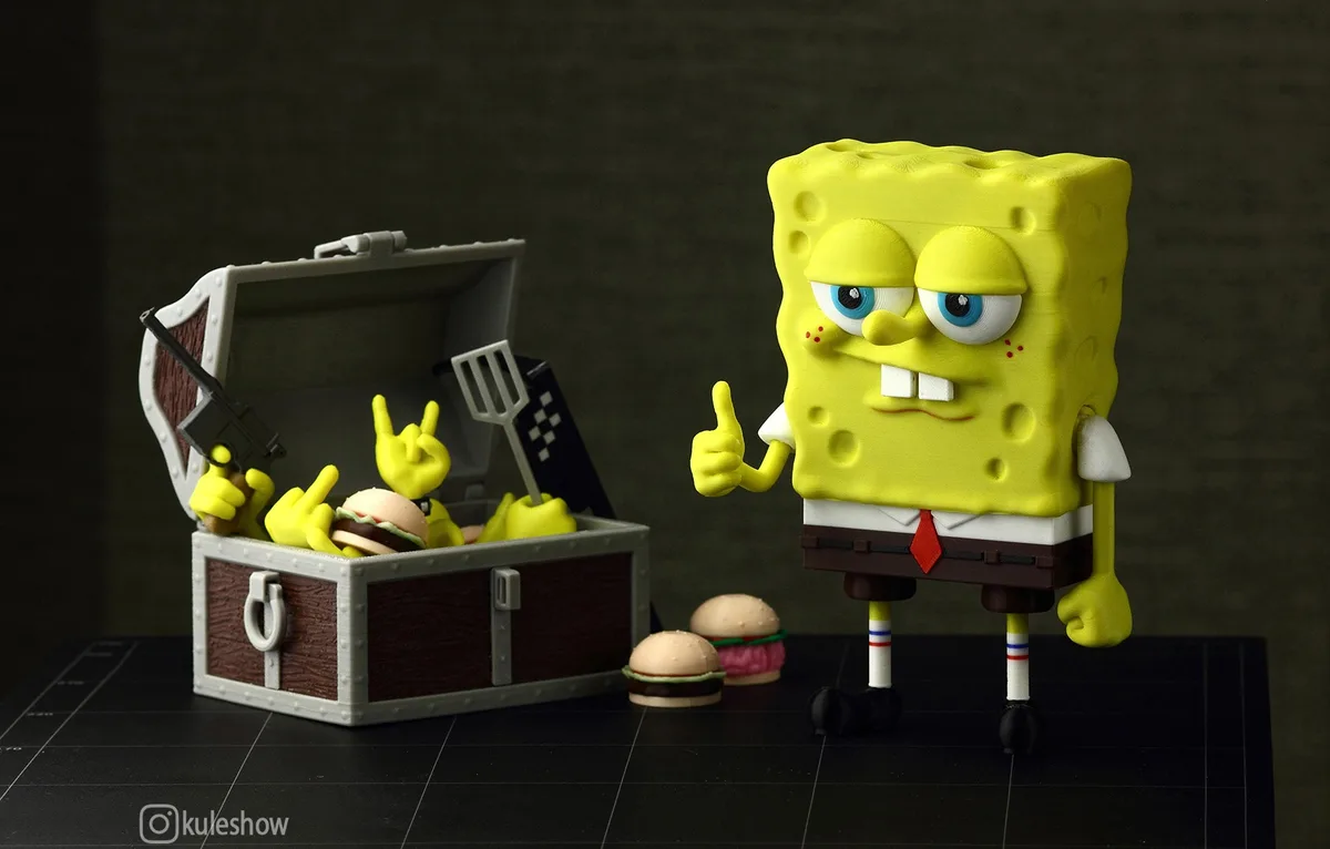 A yellow SpongeBob SquarePants figurine stands beside an open treasure chest filled with miniature SpongeBob figures holding…